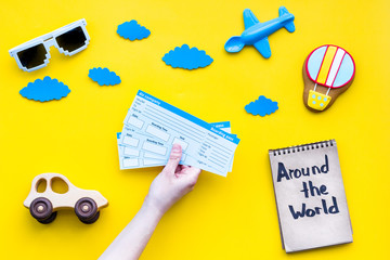 Travelling with child concept. Air balloon, car and plane. Around the world hand lettering in notebook on yellow background top view copy space