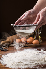 sifting flour from a strainer on a wooden table
