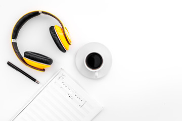 Work desk of modern composer. Music notes near headphones and coffee on white background top view copy space