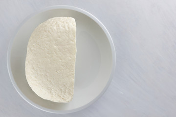 Cheese, soft cheese on a white plate, homemade cheese on a wooden table, black and white color, minimalism, Italian rustic cheese, copy space, dairy product on a wooden board, art