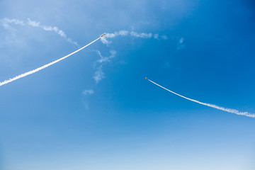 Fototapeta na wymiar A group of professional pilots of military aircraft of fighters on a sunny clear day shows tricks in the blue sky, leaving beautiful traces of clouds scattered in different directions.