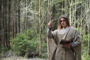 A man in a cassock spends a ritual in a dark forest