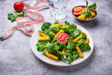 Healthy vegetable salad, water and measuring tape