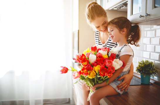 happy mother's day! child daughter   gives mother a bouquet of flowers to tulips