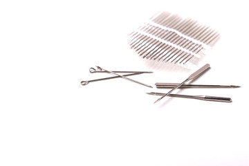 Silver sewing pins and needles on white background