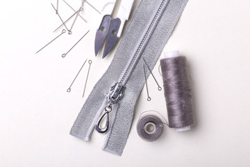 Sewing pins, scissors, zipper and plastic bobbin with colour threads