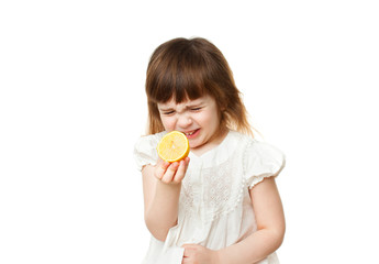 Girl 4-5 years crooked and eating lemon on white background
