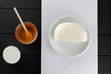 Cheese, soft cheese on a white plate, hard cheese and honey on a wooden background, minimalism,...