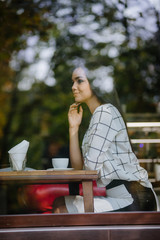 Beautiful young brunette sitting in a cafe and drinking tea.