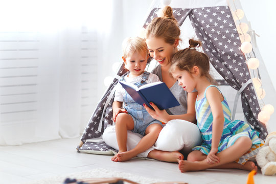 family mother reading to children book in tent at home.