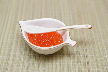 red caviar is in a white plate in the form of a leaf