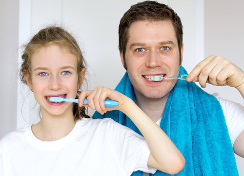 Father and his daughter brushing teeth in bathroom.