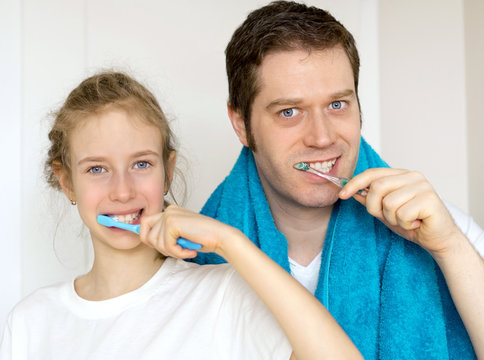 Father and his daughter brushing teeth in bathroom.