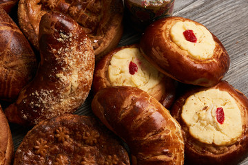 Traditional homemade Russian Easter baked goods, kulichi, patties with cottage cheese, karavai and loaf cake with nuts on festive table background