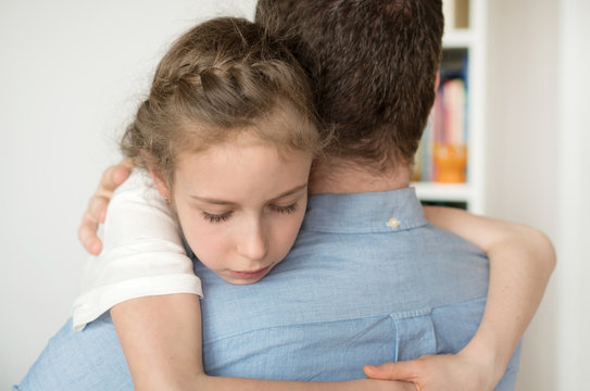 Sad little girl hugging her dad.