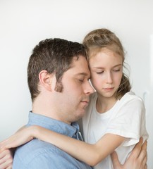 Sad little girl hugging her dad.