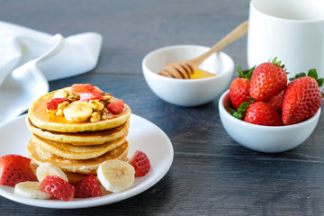 Healthy homemade breakfast with pancakes, strawberry, bananas nuts and honey