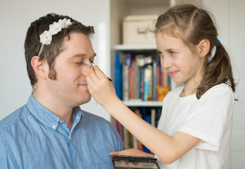 Cute little girl making makeup to her dad.