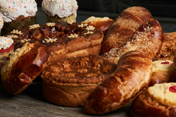 Traditional homemade Russian Easter baked goods, kulichi, patties with cottage cheese, karavai and loaf cake with nuts on festive table background