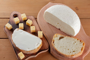 Cheese, a sandwich with soft cheese, hard cheese on a wooden board, minimalism, wooden cutlery, honey, kefir in a glass, copy space, a piece of bread, cheese, cheese pattern, French breakfast