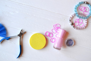 Colorful and bright cosmetics. Beauty care tools. Beauty salon. Girl's paradise.  Nail polishes, sequins, pink hair bands and comb on the white wooden desk. Bright still life of beauty instruments.