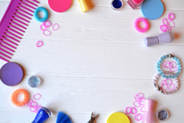 Colorful and bright cosmetics. Beauty care tools. Beauty salon. Girl's paradise.  Nail polishes, sequins, pink hair bands and comb on the white wooden desk. Bright still life of beauty instruments.