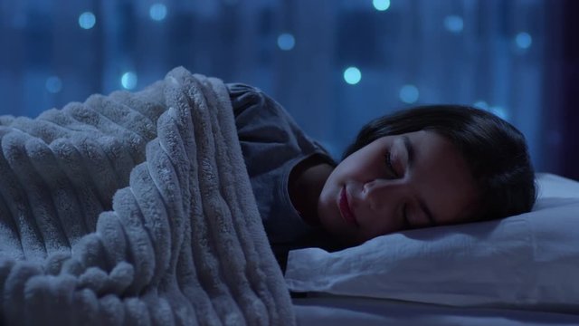 Girl sleeping on a bed at Christmas night and waking up with happy emotion. Shot on RED Cinema Camera.