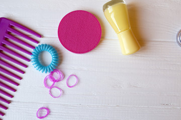 Colorful and bright cosmetics. Beauty care tools. Beauty salon. Girl's paradise.  Nail polishes, sequins, pink hair bands and comb on the white wooden desk. Bright still life of beauty instruments.