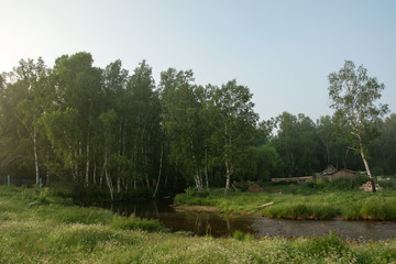 Small mountain stream with bottom of stones flows along village.