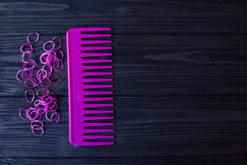 Beauty care tools. Beauty salon. Girl's paradise. Pink hair bands and comb on a dark blue wooden desk. Bright still life of beauty instruments.