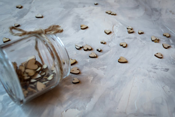 Wooden hearts in a jar on a grey textured background. Stylish still life. 
