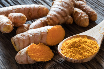 Turmeric powder on a spoon and fresh turmeric root