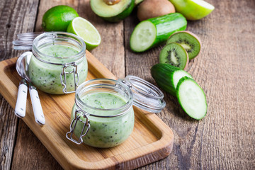 Healthy green yogurt sauce in glass jar with ingredients