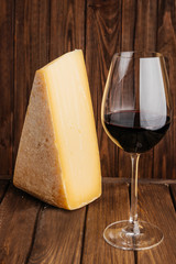 Cheddar Cheese and Glass of Red Wine on Wooden Brown Background.