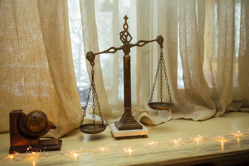 Old vintage balance scale with bowls and several coins in one of the bowls on a light wooden table....