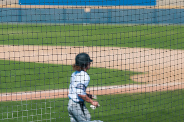 Obraz premium Baseball teenager behind the net
