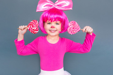 Girl clown holds two candies near the ears toothy smiling