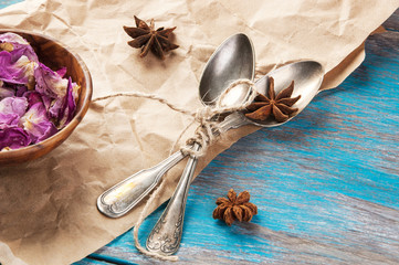 Vintage tea spoons and rose petals on wooden blue background
