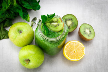 Green smoothie with spinach, apple, kiwi  and mint  in a jar mug on gray stone. The concept of healthy nutrition and diet. Top view