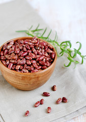 Obraz na płótnie Canvas Raw red kidney beans in wooden bowl, rosemary herb, healthy vegetarian food, lunch