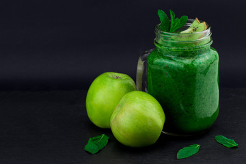 green smoothie with fruits and vegetables on black background. With copy space