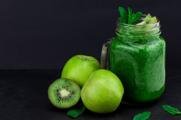 green smoothie with fruits and vegetables on black background. With copy space