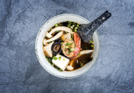 Traditional Japanese miso soup with king prawns and tofu as top view in a bowl with copy space