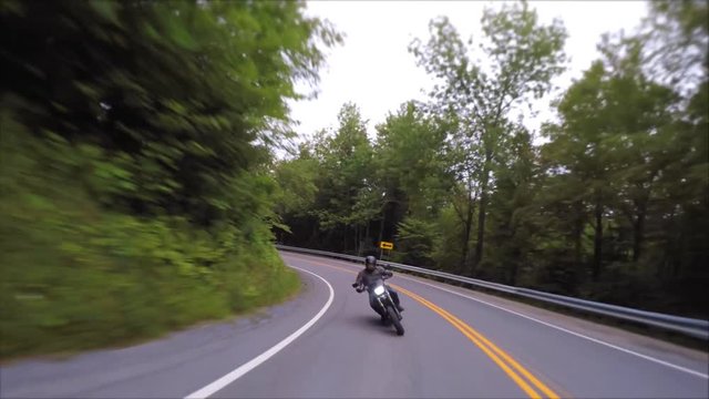 motorcycles race through twisty forest roads close together