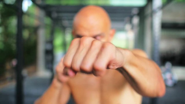 Boxer man making hits with fists without gloves while training boxercise