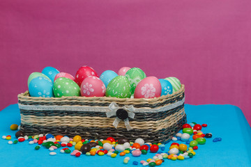 Colored Easter eggs in a basket on a blue-pink background.