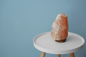 Himalayan salt lamp on table against color background