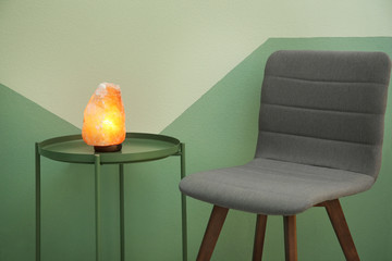 Himalayan salt lamp on table near color wall
