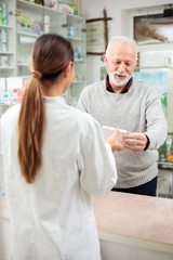 Medicine, pharmaceutics, health care and people concept - Female pharmacist selling medications to senior male customer