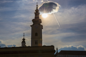 Obraz premium Silhouette of the Clock Tower Of St Mary Church on the sunset backlight with a cloud hiding the sun, Zagreb, Croatia